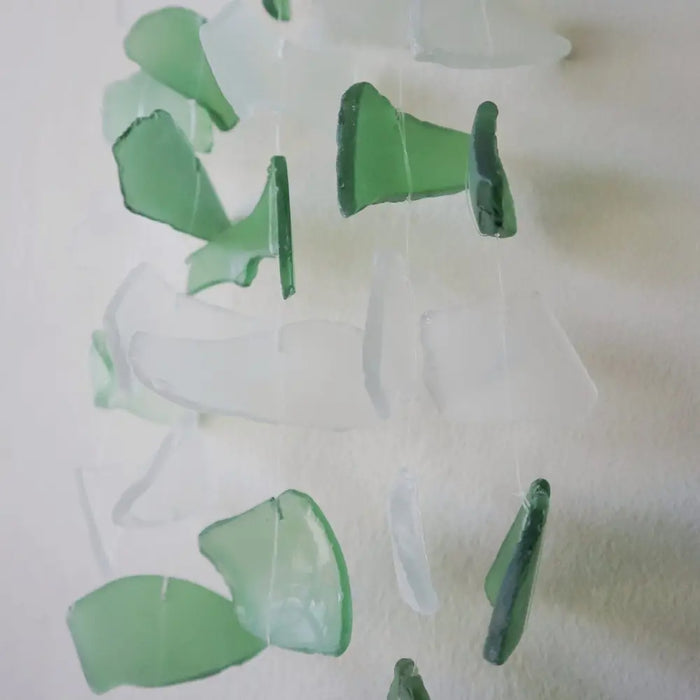 Green and white capiz shell and glass wind chime with translucent sea glass pieces hanging by thin strings
