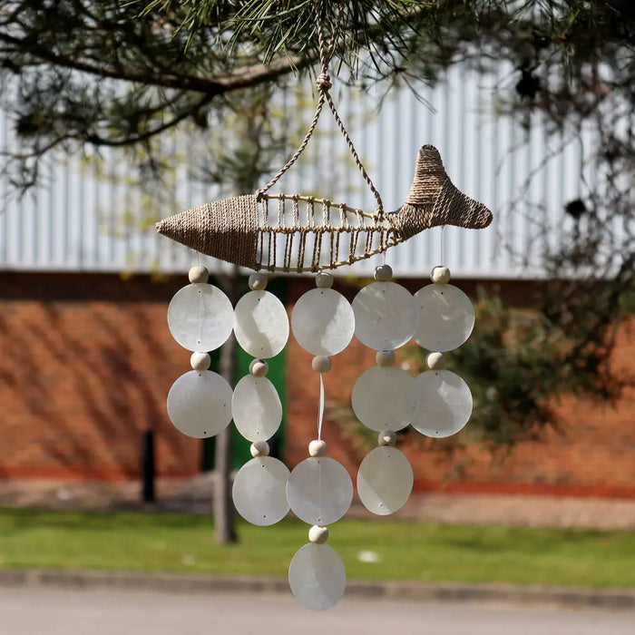 Handwoven raffia fish wind chime with natural fiber body and capiz shells hanging on five strings in white and natural tones