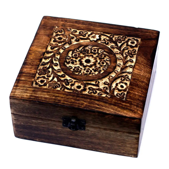 A dark brown mango wood aromatherapy box with floral carvings and a black metal clasp holds essential oils