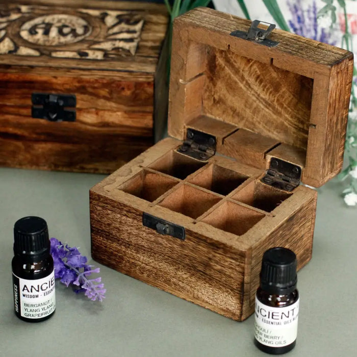 A carved mango wood aromatherapy box with six compartments and black metal hinges for essential oils storage