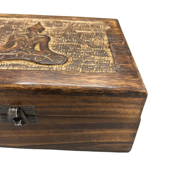 A rustic dark brown mango wood keepsake box with an intricately carved golden brown Buddha emblem and metal latch
