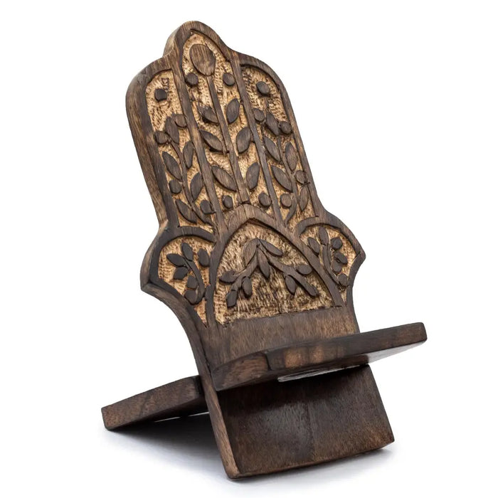 Hand carved dark mango wood phone stand shaped like a hamsa hand with intricate leaf and dot patterns