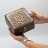 A dark brown carved mango wood tea box with gold floral details and four compartments with a vintage metal clasp
