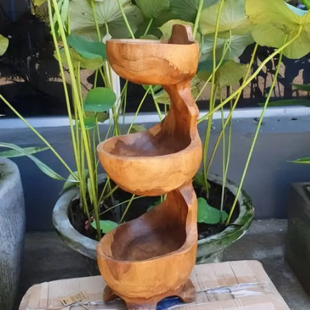A three-tiered teak standing bowl fountain with smooth rounded edges and a natural light brown finish