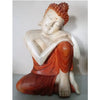 A serene seated buddha statue carved from suar wood with a white-painted body and orange-red robes measuring 30cm