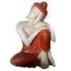 Carved wood buddha statue thinking in smooth suar wood with white and reddish orange robe seated calmly
