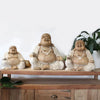 Three carved wood happy buddha statues with whitewash finish wearing pearl necklaces made of suar wood