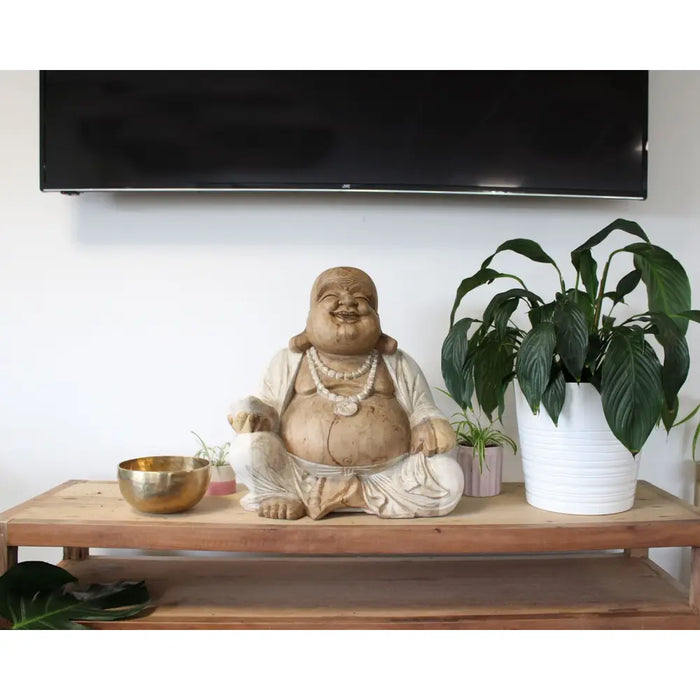 A carved wood happy buddha statue with a whitewash beige finish made from suar wood and detailed robes with pearl necklaces