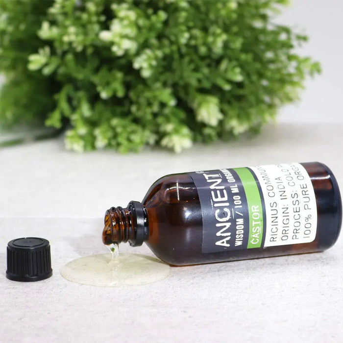 A dark amber glass bottle of castor organic base oil 100ml with a black screw cap and organic origin label