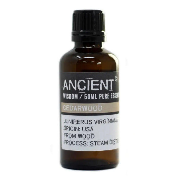 A dark amber glass bottle with black cap labeled ancient wisdom 50ml pure cedarwood essential oil with allergen info