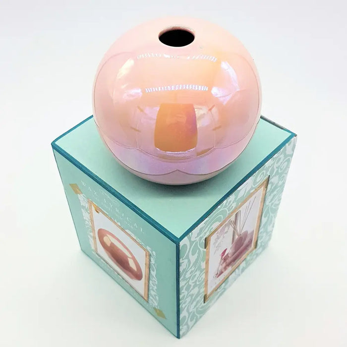 A glossy peach ceramic ball reed diffuser vase with a subtle iridescent sheen and a hole at the top