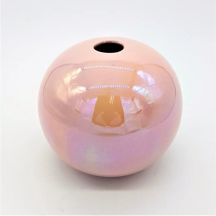 A glossy pink ceramic ball reed diffuser vase with a smooth spherical shape and a hole at the top