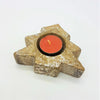A rustic gold star shaped tealight holder with glitter holding a bright orange candle for christmas tree decor