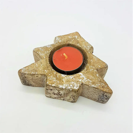 A rustic gold star shaped tealight holder with glitter holding a bright orange candle for christmas tree decor