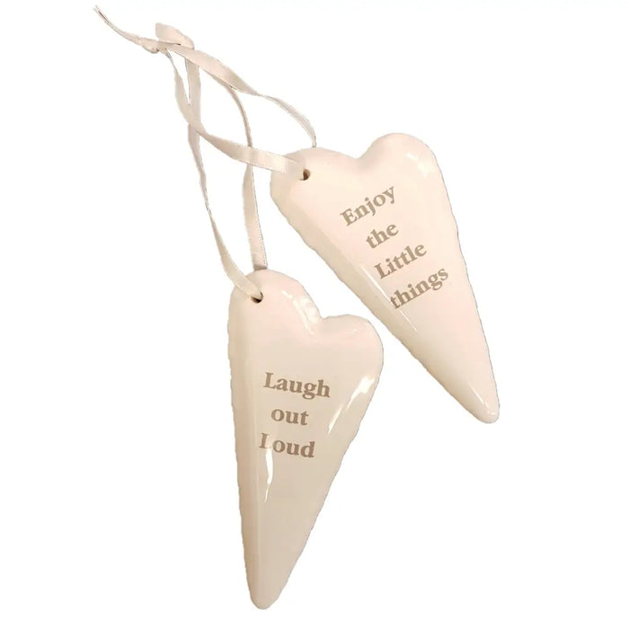 Cream-colored ceramic heart hanging ornaments with engraved motivational phrases and satin ribbon loops