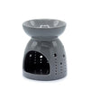 Gray ceramic oil burner with a smooth glossy finish and decorative perforations along its sides