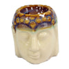 Cream-colored ceramic oil burner shaped like a Buddha head with a glazed patterned top in brown and blue tones