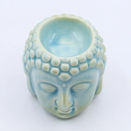 A light blue ceramic buddha head oil burner with detailed facial features and a glossy finish for incense or oils