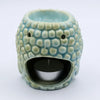 A pastel blue ceramic oil burner shaped like a smiling textured creature with small eye holes and rounded bumps