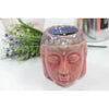 Pink ceramic oil burner shaped like a buddha head with a blue and gold glazed top rim in a simple setting
