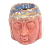 A ceramic oil burner shaped like a buddha head with a glossy peach face and blue yellow speckled rim