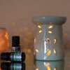 A light gray ceramic oil burner with leaf cutouts and glowing amber lights in the ceramic oil burner dragonfly white design