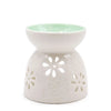 White ceramic oil burner with teal floral cutout patterns and a mint green interior for burning oils