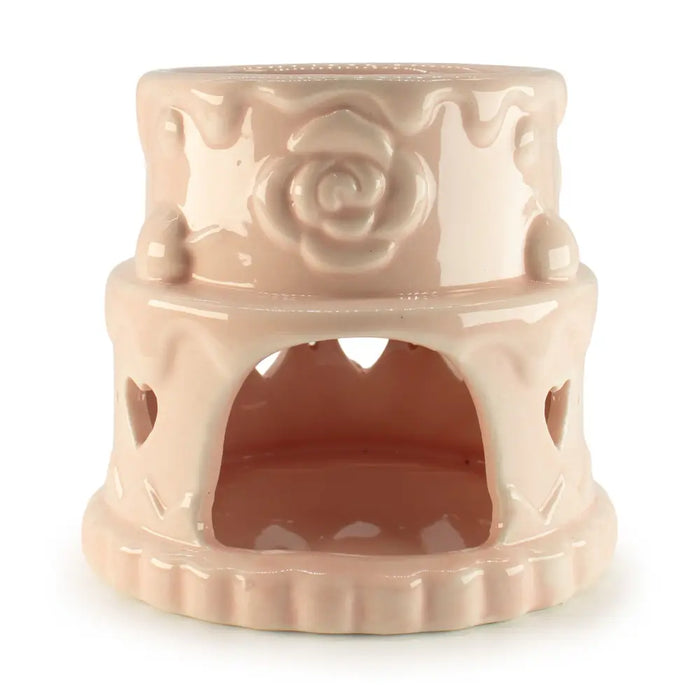 A blush pink ceramic oil burner with rose details and heart-shaped cutouts for warming candles or oils