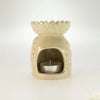 Cream-colored ceramic oil burner shaped like a lotus with carved floral pattern and silver tea light candle inside