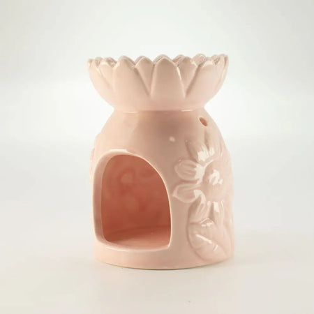 A pastel pink ceramic oil burner shaped like a lotus flower with floral embossing and an arched opening