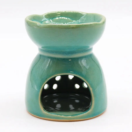 A teal ceramic oil burner with scalloped rim and white dots on front panel for burning essential oils