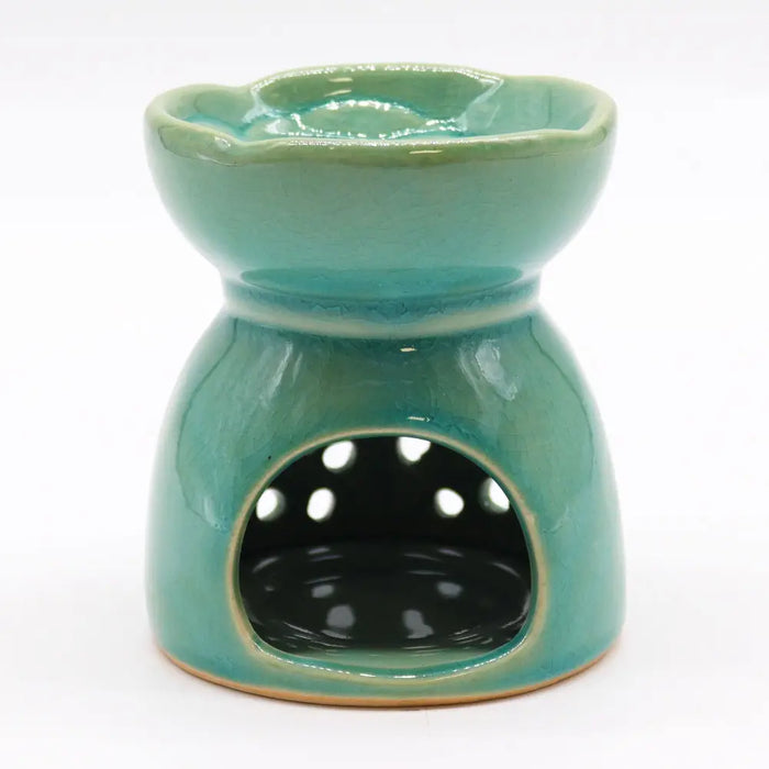 A teal ceramic oil burner with scalloped rim and white dots on front panel for burning essential oils