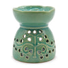 A teal ceramic oil burner with a scalloped rim and tree of life cutouts for essential oil use