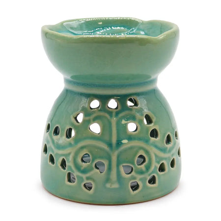A teal ceramic oil burner with a scalloped rim and tree of life cutouts for essential oil use