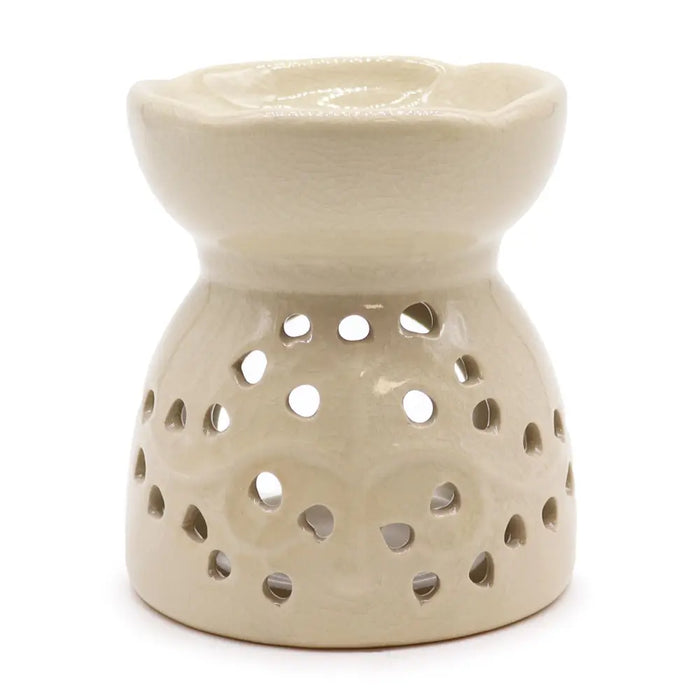 Cream-colored ceramic oil burner with fluted rim and tree of life design on decorative perforated base