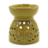 A lime green ceramic oil burner with tree of life pattern and circular cutouts for essential oils