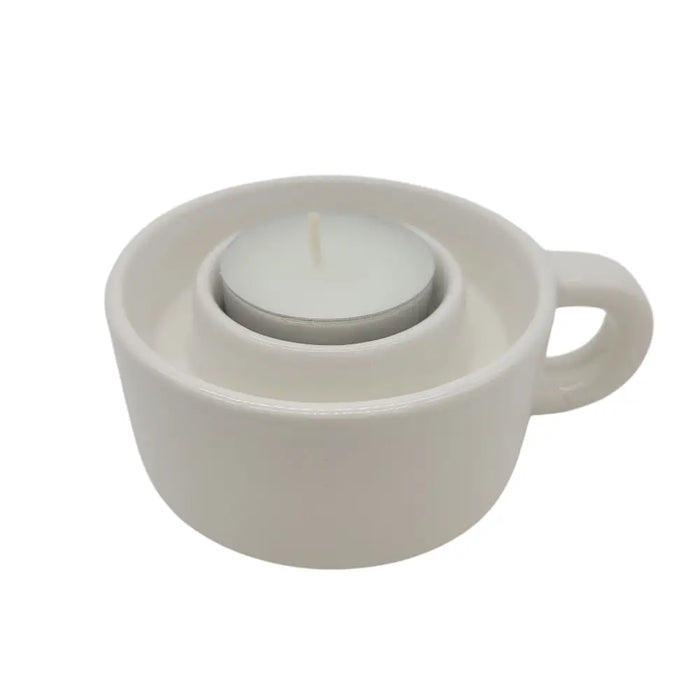White ceramic candle holder shaped like a coffee cup with a small white tealight candle inside