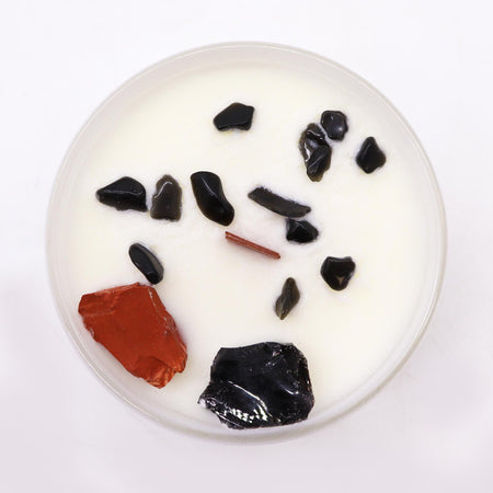 White candle with black and red stone fragments in wax for root chakra balance chakra crystal candle