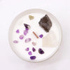 A white candle in a glass jar with amethyst, obsidian, and quartz stones for crown chakra spiritual connection