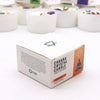 White cardboard box with sacral chakra crystal candle label in orange and black featuring a meditating figure silhouette