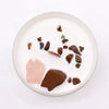 A white candle with colorful polished gemstones embedded in wax for sacral chakra creative passion use