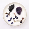 A white candle with a clear glass rim featuring multicolor stones for solar plexus chakra self-assurance use