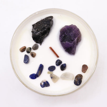 A white candle with a clear glass rim featuring multicolor stones for solar plexus chakra self-assurance use