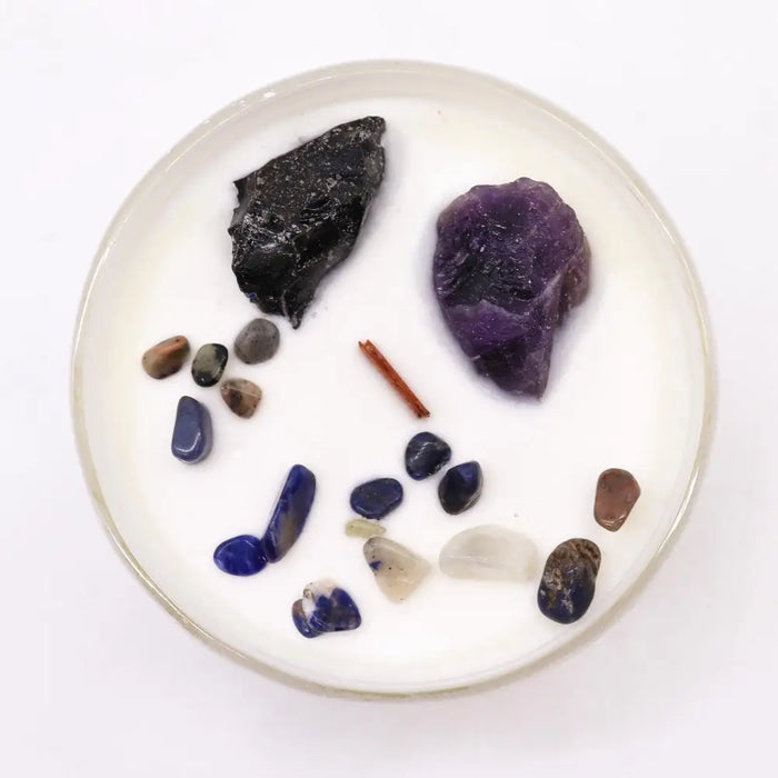 A white candle with a clear glass rim featuring multicolor stones for solar plexus chakra self-assurance use