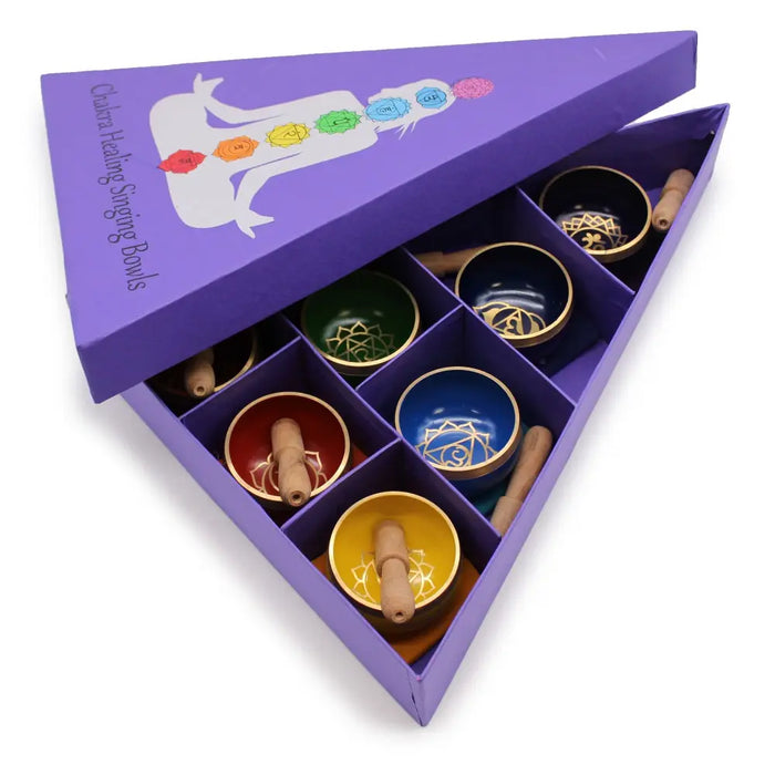 Set of seven colorful chakra singing bowls with golden designs and wooden mallets in a purple gift box bowl gift set