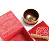 A red and gold chakra singing bowl with a golden root chakra symbol engraved on its inner surface
