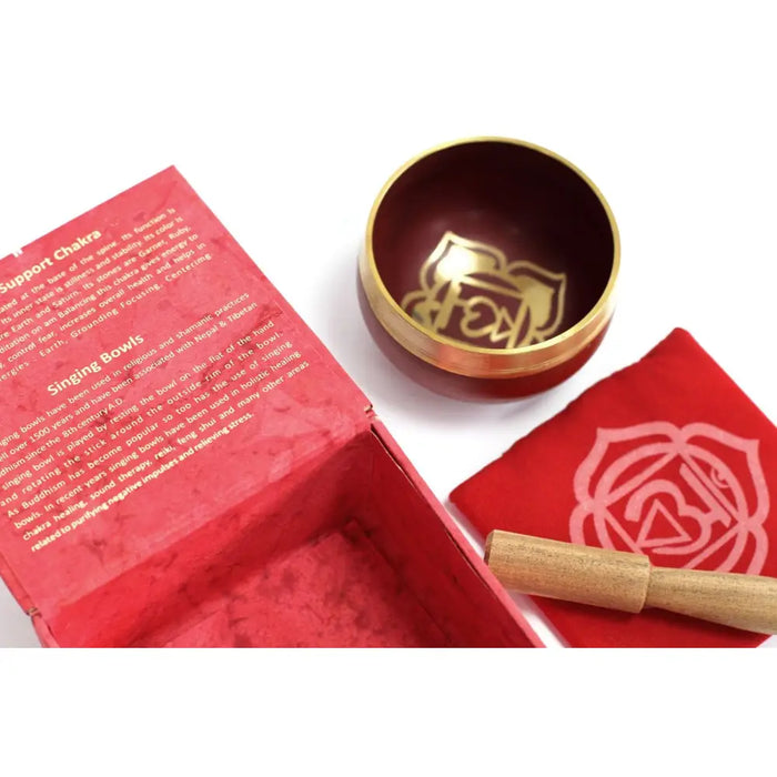 A red and gold chakra singing bowl with a golden root chakra symbol engraved on its inner surface