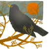 A blackbird with a yellow beak and eye on golden branches against a teal sky on a mary fedden christmas card pack