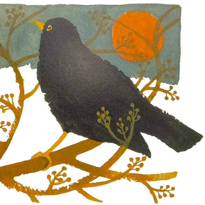 A blackbird with a yellow beak and eye on golden branches against a teal sky on a mary fedden christmas card pack