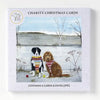 A charity christmas card pack by hannah cole featuring two dogs in festive sweaters on a snowy background